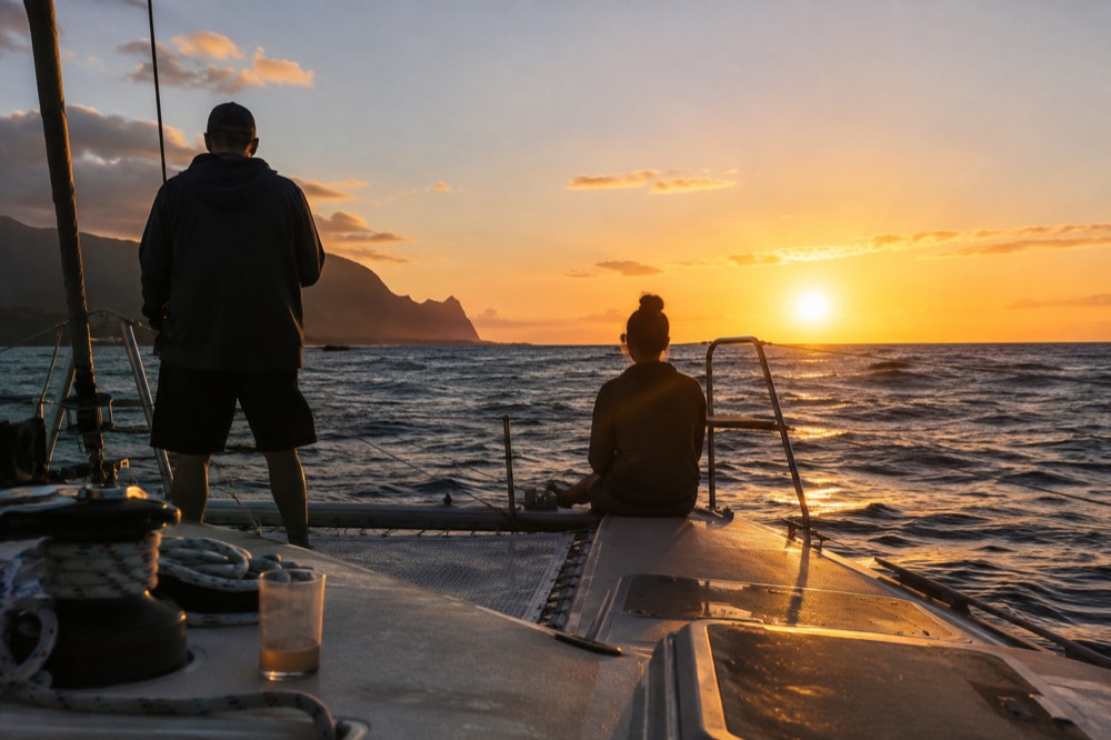 A catamaran's stern rail at golden hour heading west from Port Allen