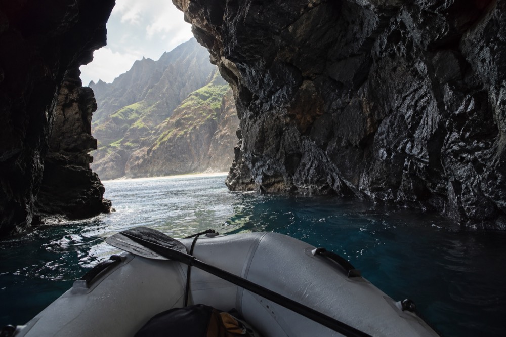 A rigid inflatable raft floating in the mouth of a sea cave with dark rock walls