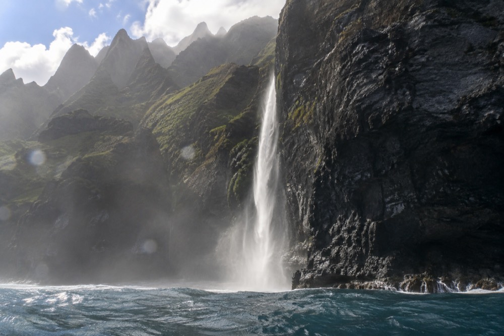 Morning sunlight on the sea cliffs and a waterfall along the Napali Coast