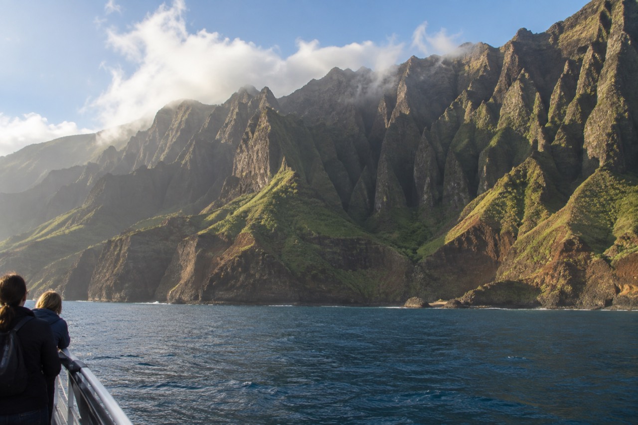 Sunlight over the Napali Coast with calm ocean and green ridges