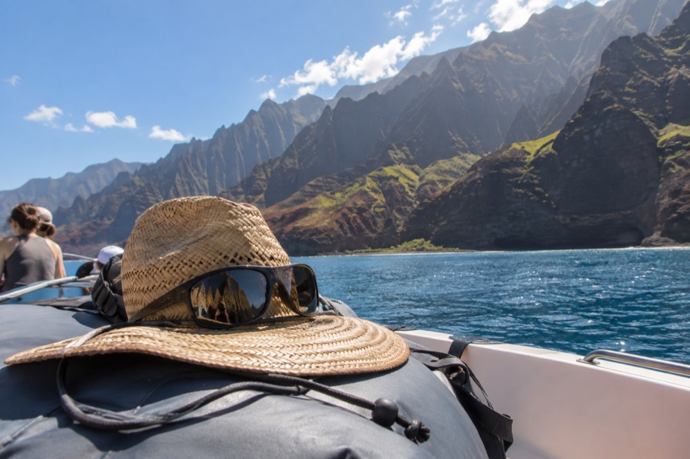 A boat bow with a brimmed hat and polarized sunglasses resting on a dry bag in bright sunlight