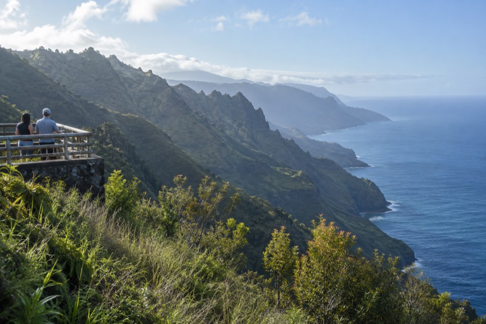 A green ridge above the ocean with deeply eroded cliffs fading into haze