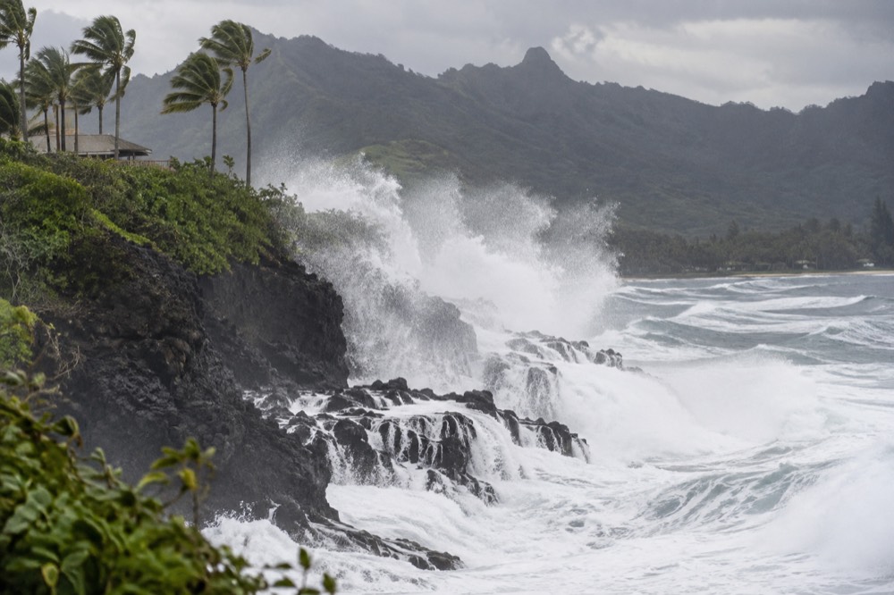 Large winter waves breaking against a dark cliff face on an exposed coastline