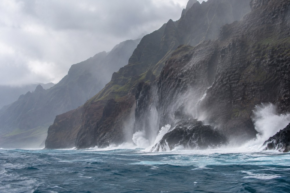 Large winter waves breaking against the base of sea cliffs along a rugged coastline