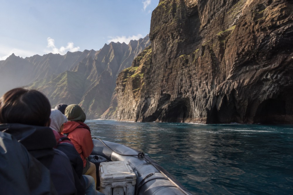 A rigid-hull inflatable raft cruising close to the Napali cliffs on calm water