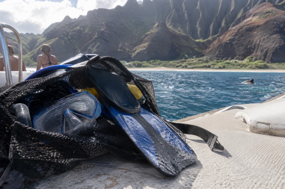 A mesh bag of snorkel masks and fins laid out on a boat deck