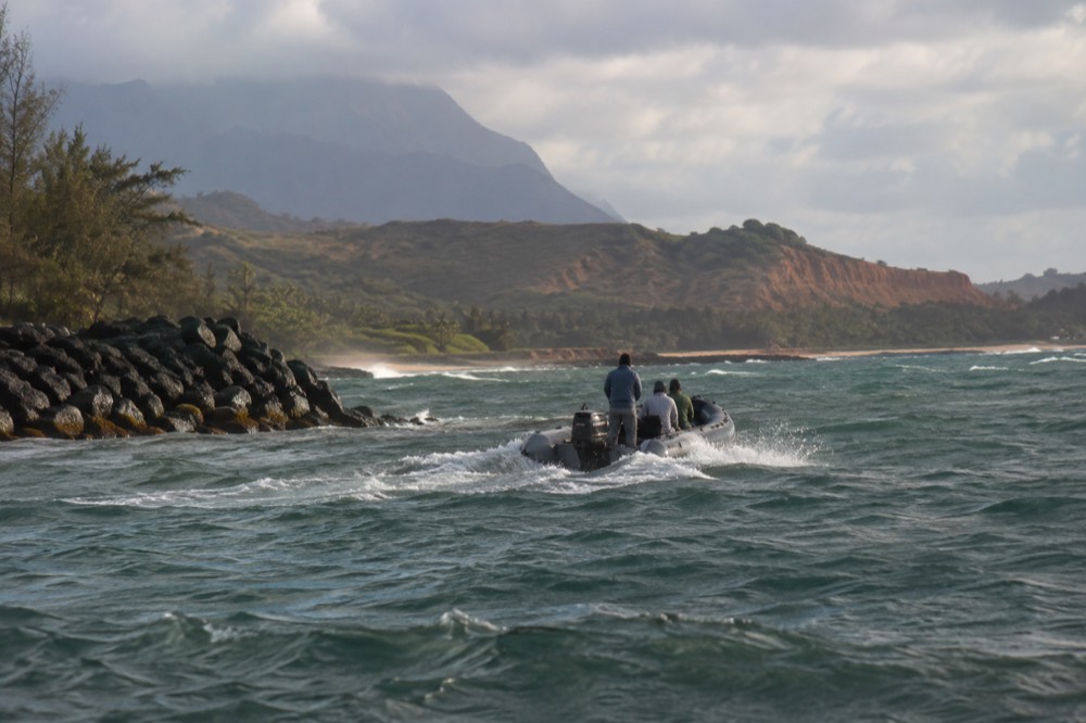 A shallow-draft tour raft works out through choppy open water off Kikiaola near Waimea