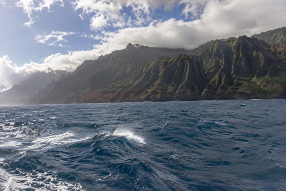 Open ocean water with whitecaps and distant sea cliffs under a partly cloudy sky