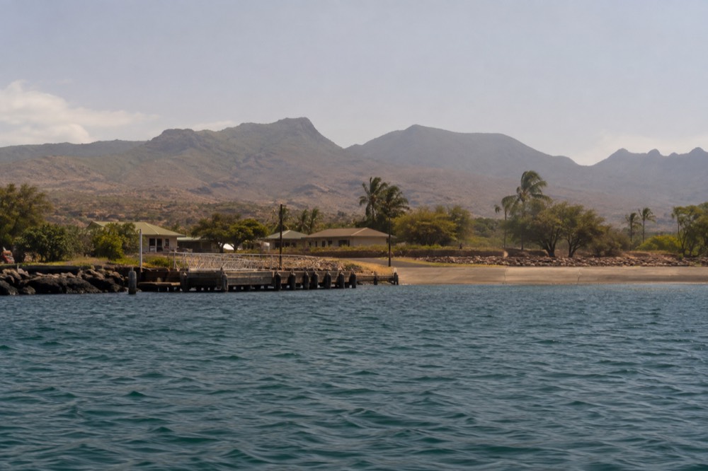 Seen from a tour boat already clear of the shore, the low tour-office row at Waialo Road on Kauai