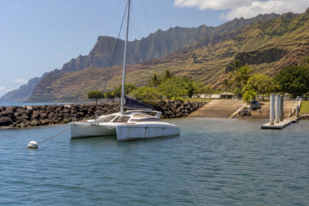 A boat docked at Port Allen Small Boat Harbor with the west-side hills in the background